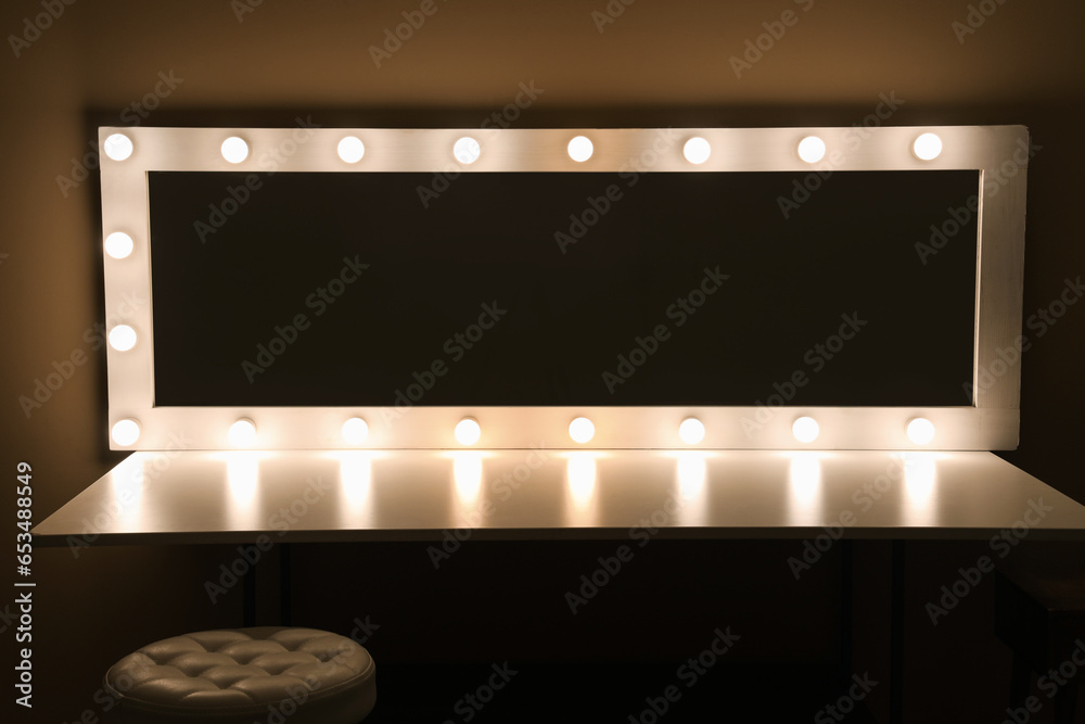 Dressing table with glowing mirror in dark makeup room