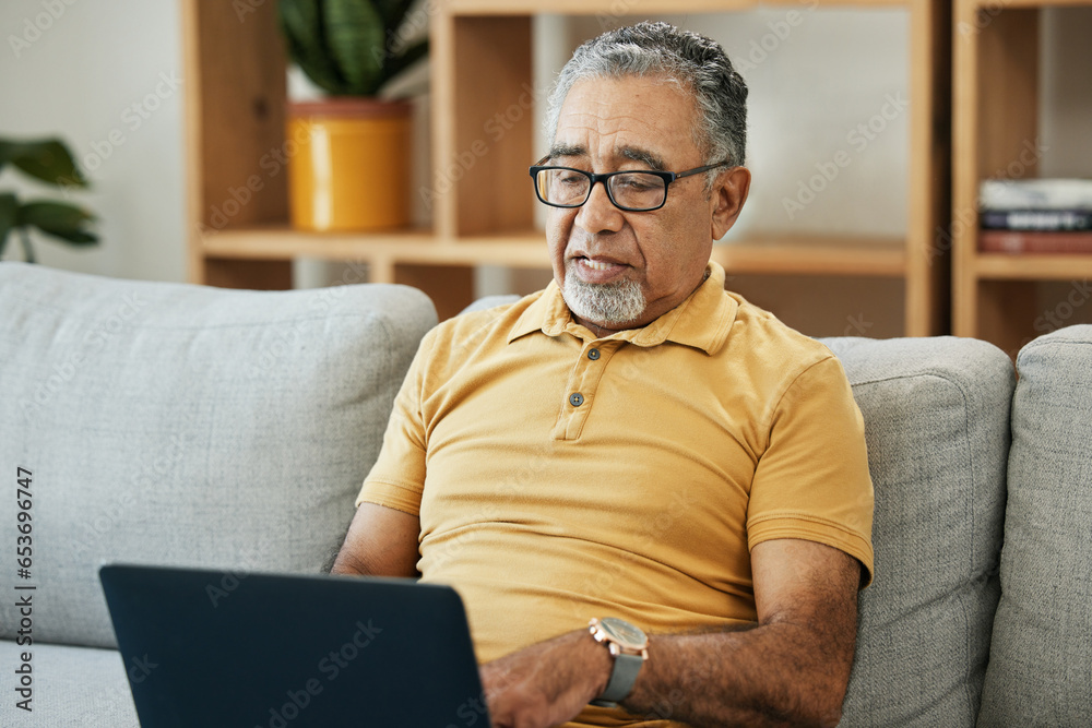 Senior man, typing and laptop on sofa in home with online research in living room or streaming video, movies or tv show. Elderly, person or writing on computer in retirement for blog or communication