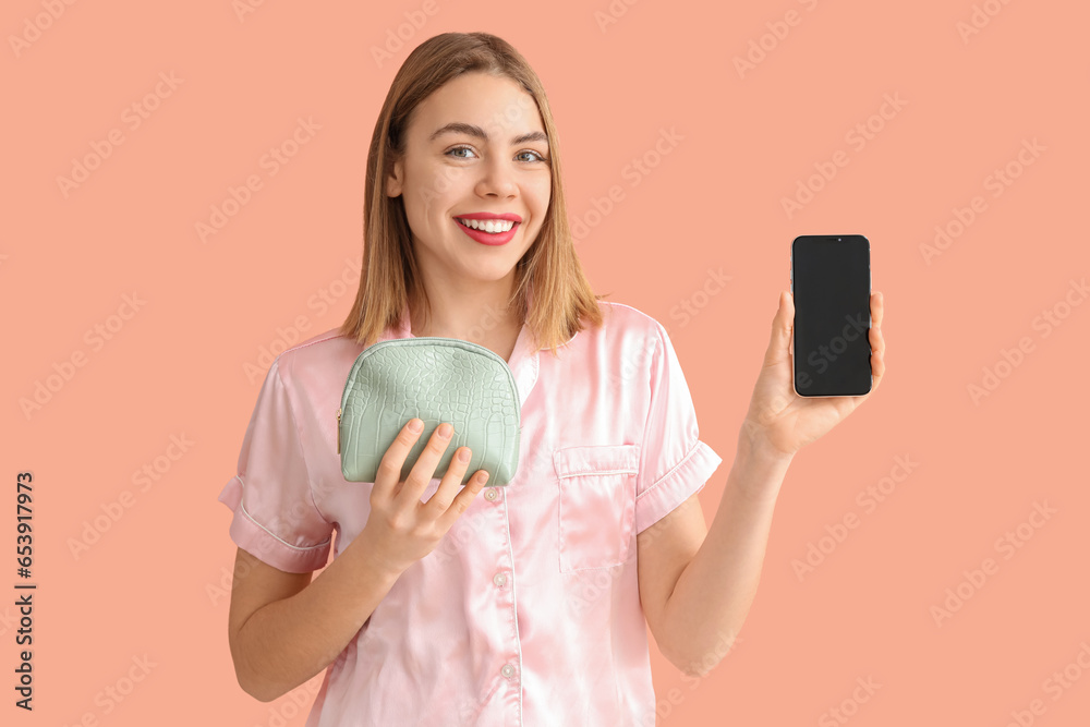 Young woman with cosmetic bag and mobile phone on pink background