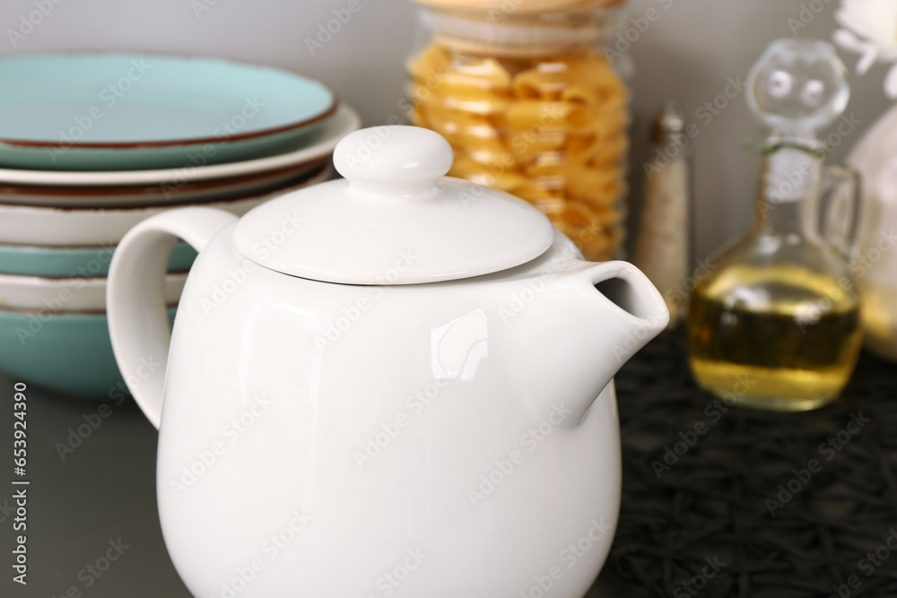 Teapot with different kitchen stuff on black table