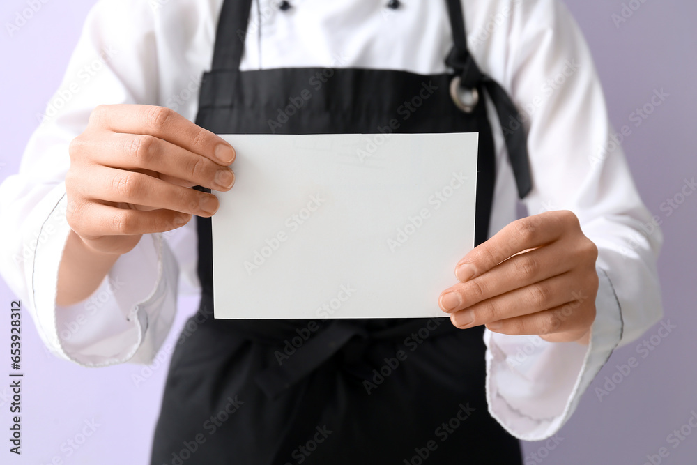 Female chef holding blank card on purple background, closeup