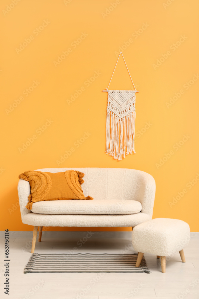 Cozy white sofa and ottoman near orange wall with wicker decor