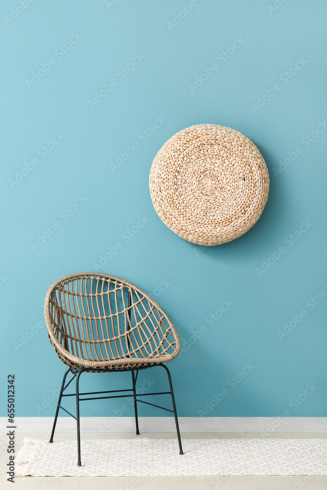 Cozy armchair and hanging wicker pouf near blue wall