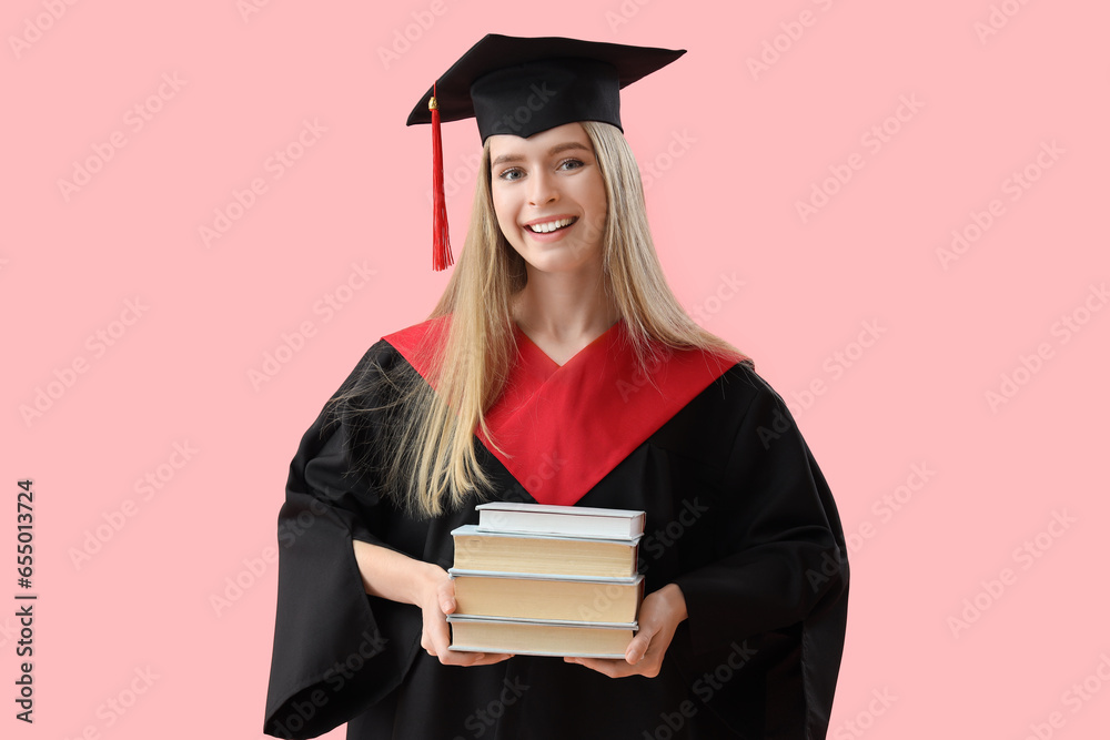 Female graduate student with books on pink background