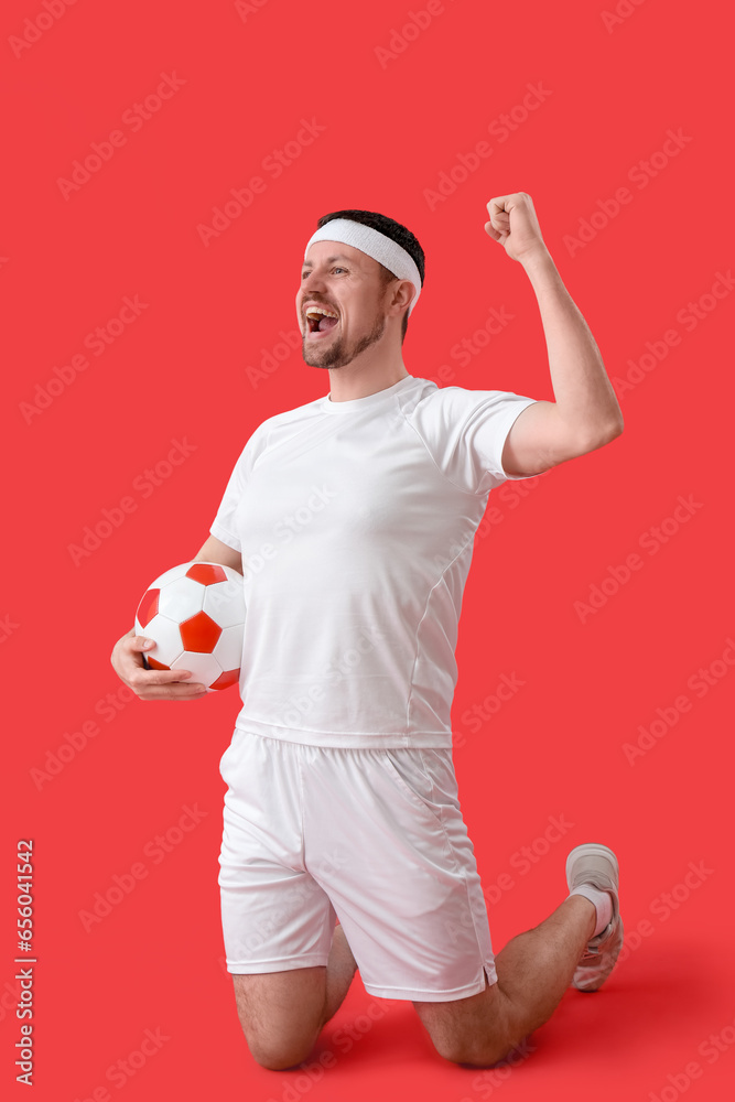 Happy soccer player with ball on red background