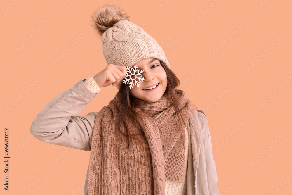 Cute little girl in winter clothes with snowflake on beige background