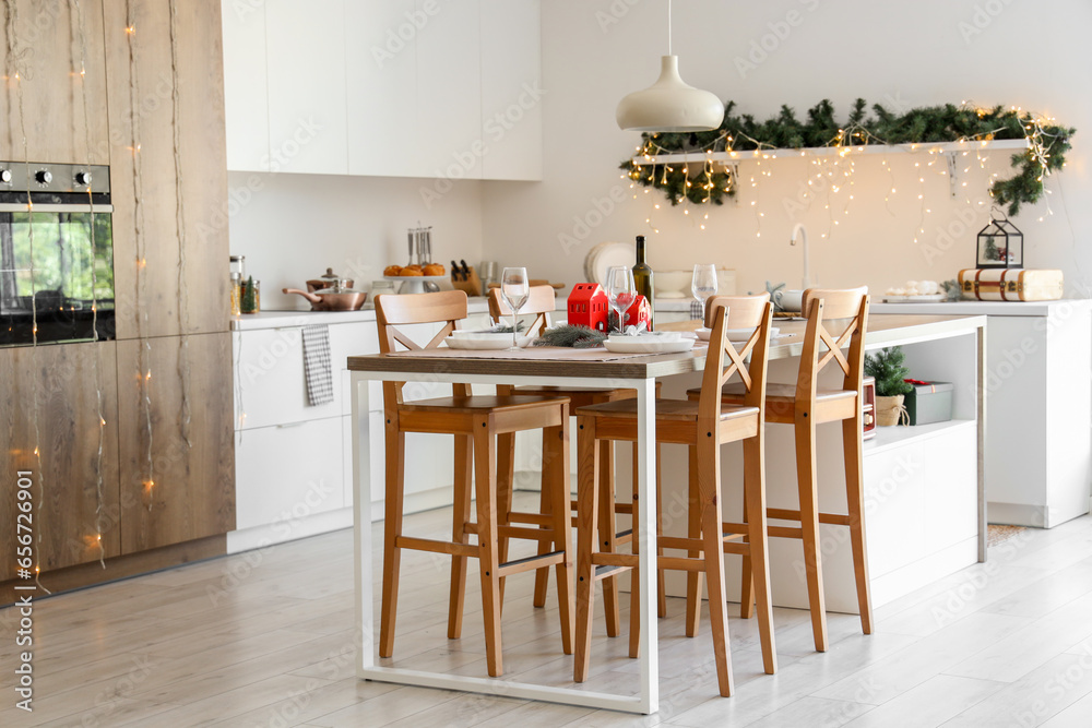 Interior of modern kitchen with festive table setting and Christmas decorations