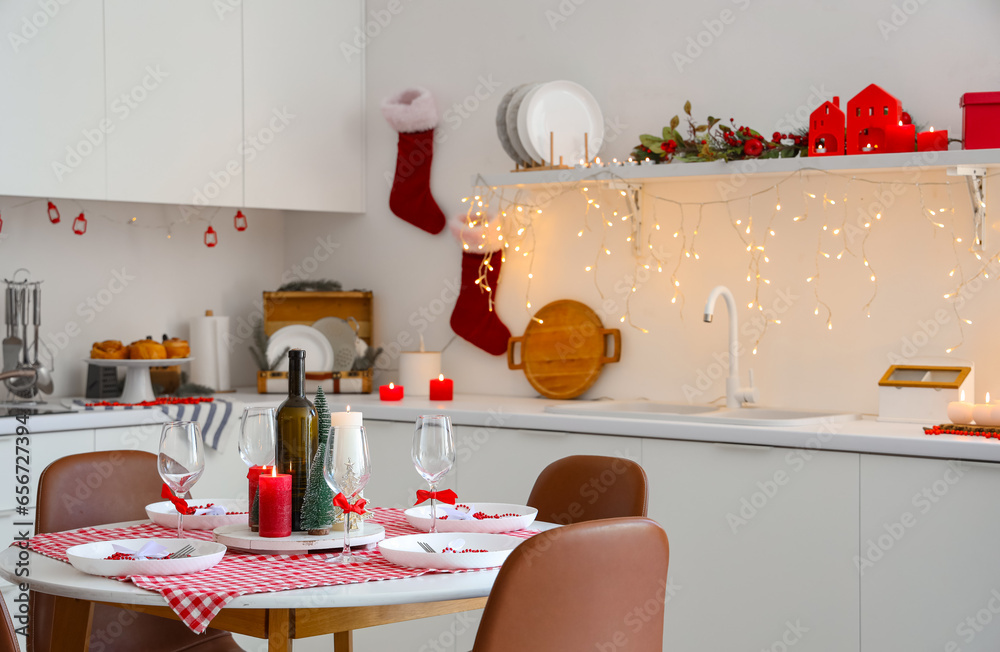 Interior of modern kitchen with festive table setting, glowing lights and Christmas decorations