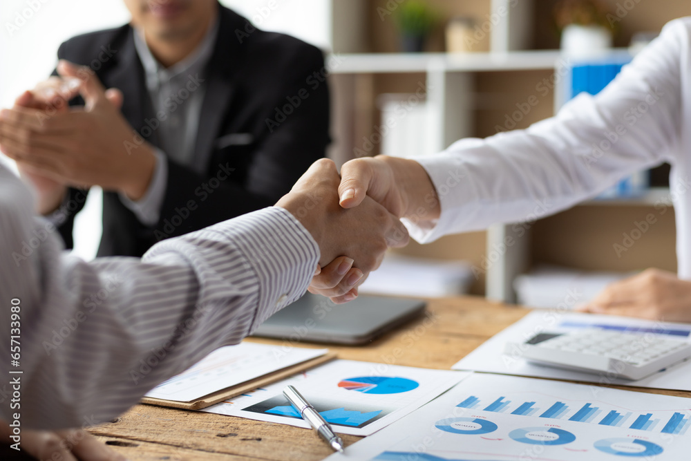Businesswoman shaking hands with financial advisor at meeting in office.