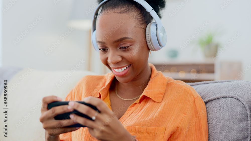 Phone games, headphones and woman in home on sofa for playing online gaming, podcast subscription or connection. Happy african person, video game or smartphone in living room for streaming multimedia