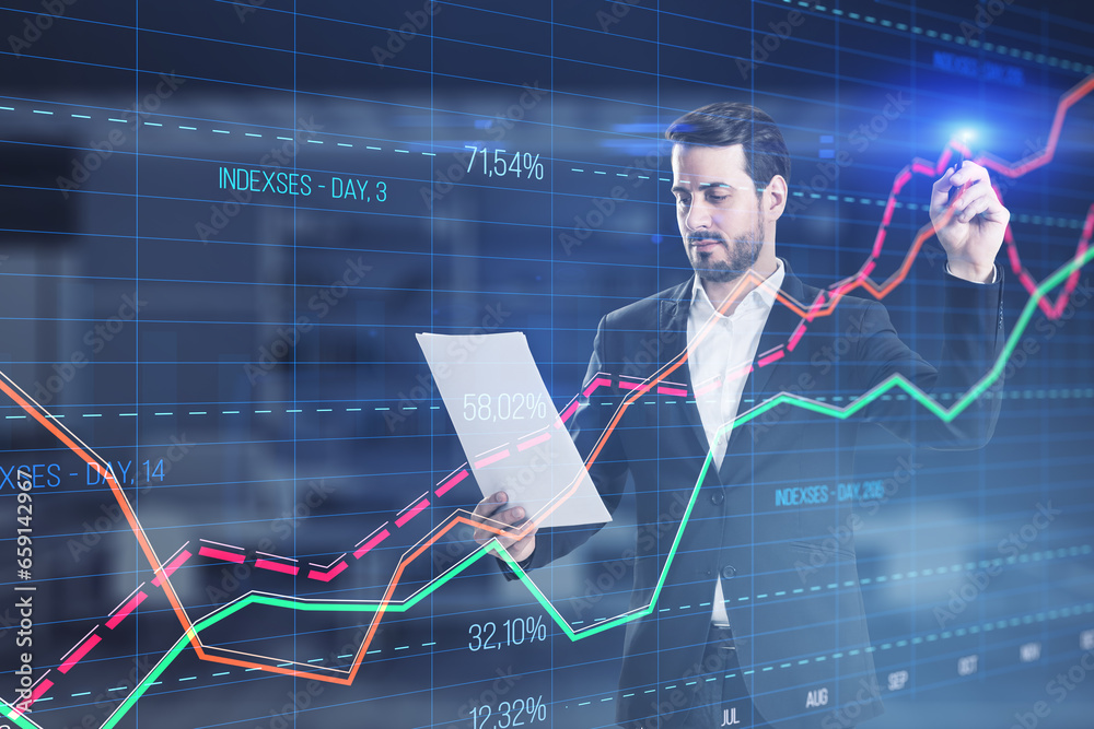 Attractive young businessman with document using creative business graph with index and grid on blurry office interior background. Stock market and financial statistics concept. Double exposure.