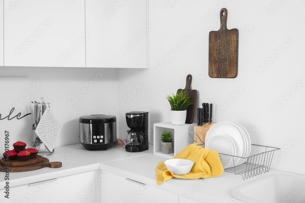 White kitchen counters with coffee machine, multi cooker and utensils