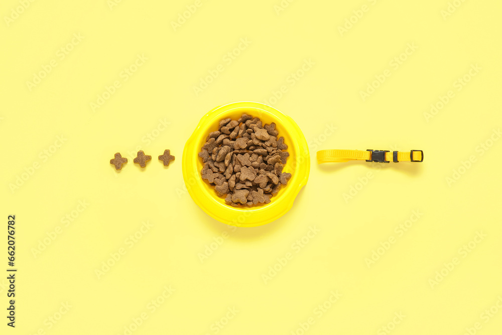 Bowl of dry pet food and collar on yellow background