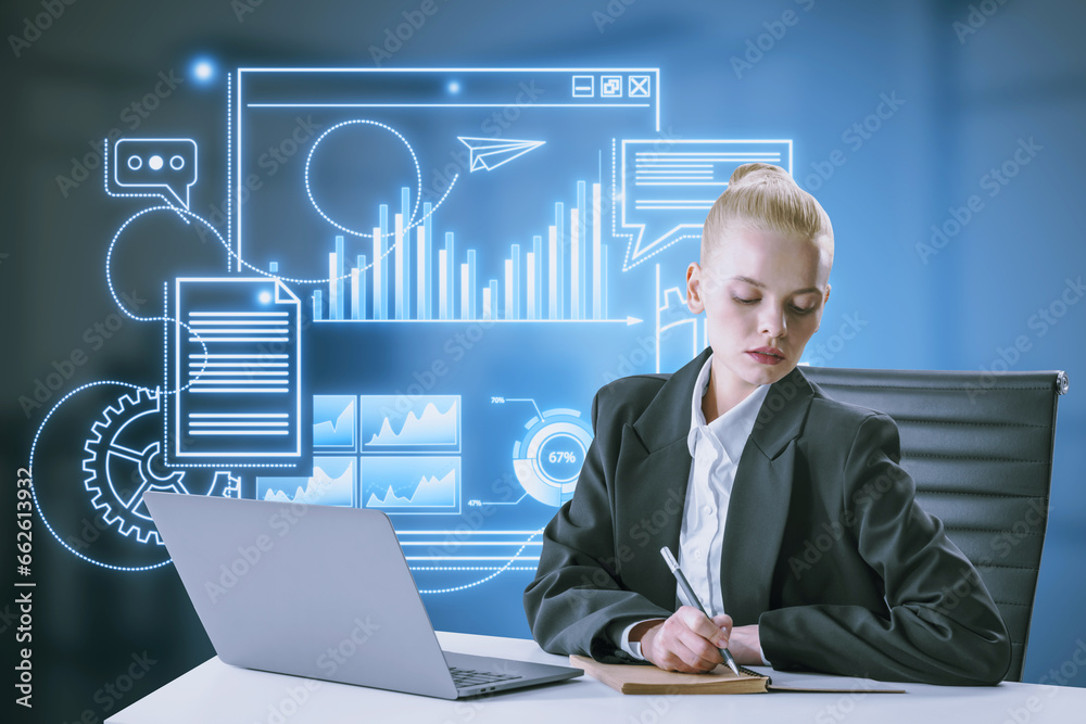Blonde young businesswoman doing paperwork at desk with laptop and blue devices hologram on blurry office interior background. Digital marketing, social network and online service concept.
