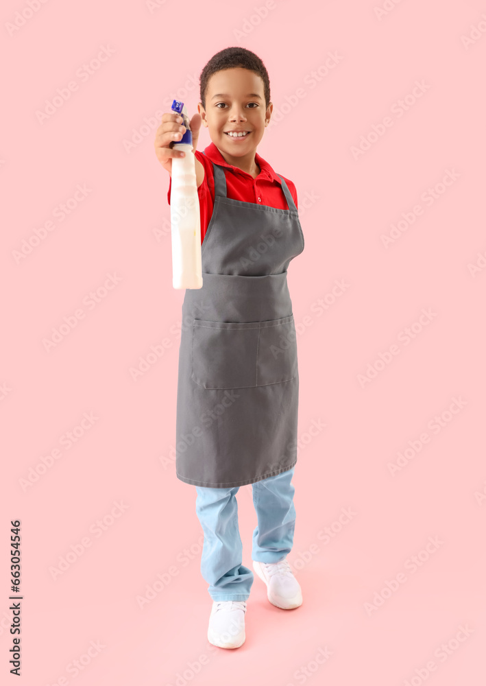 Cute African-American boy with detergent bottle on pink background