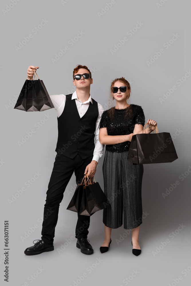 Young couple with shopping bags on grey background. Black Friday sale