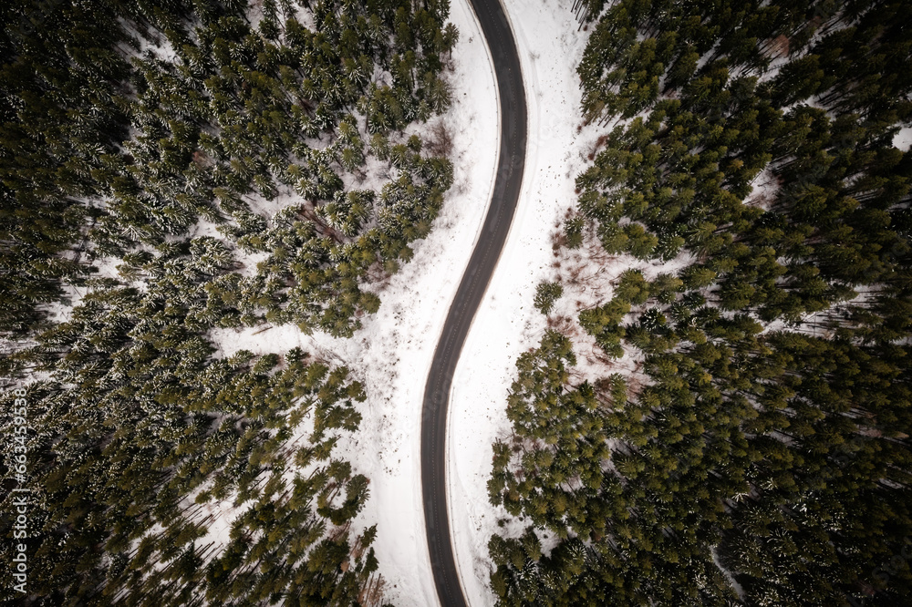Snowy forest with road serpentine in winter mountains. Top down view. Landscape photography