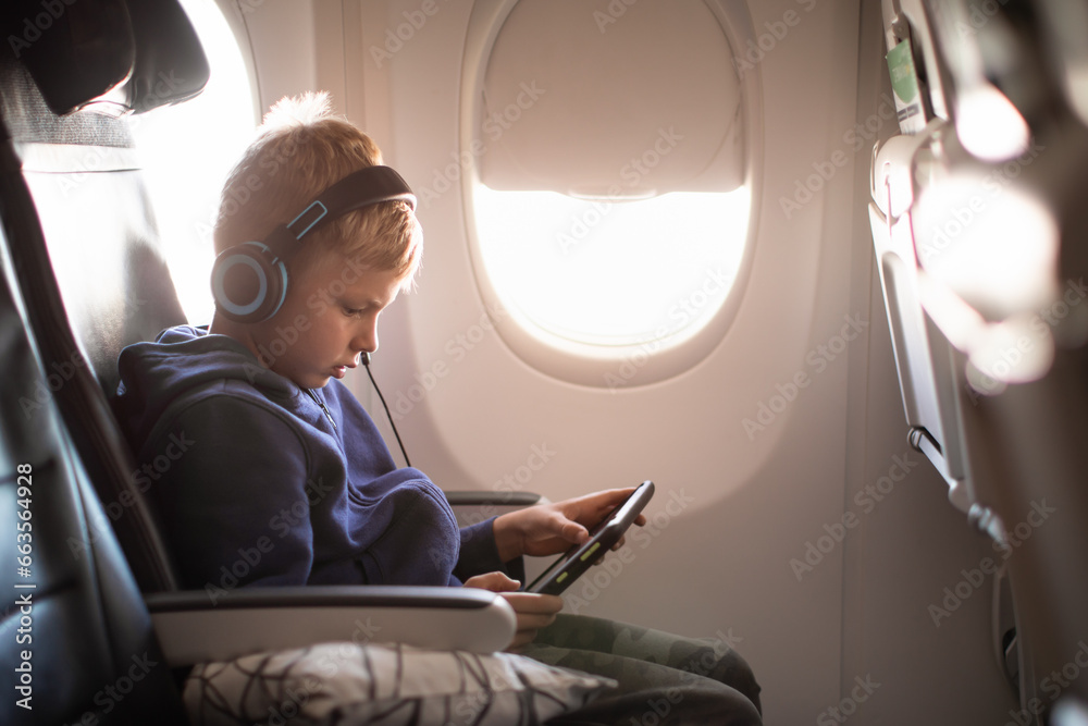 Little boy traveling on airplane using a tablet 