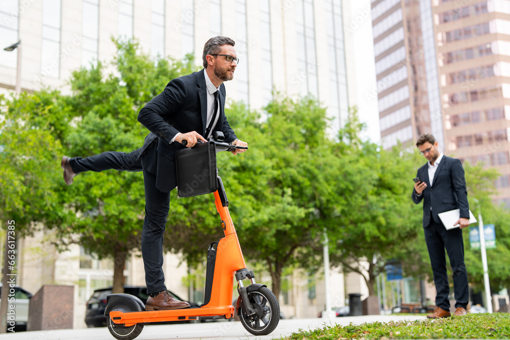 Funny excited business man on electric scooter on city street. Employee business man in suit corporate lawyer in suit riding e-scooter. Business man in a suit riding on scooter on a business meeting.