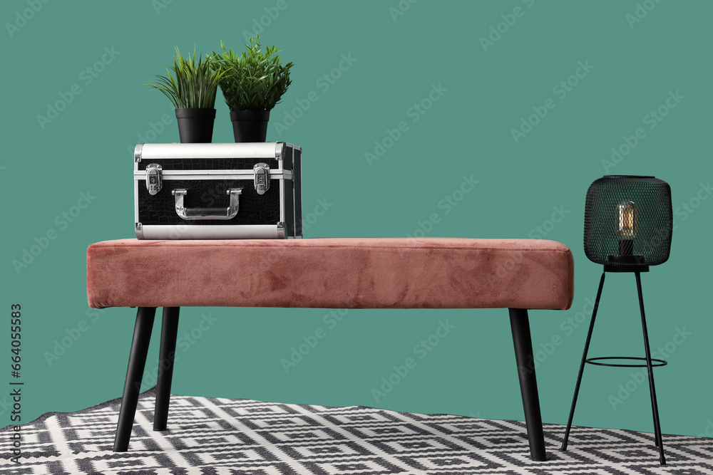 Soft bench with case, plants, lamp and carpet on green background