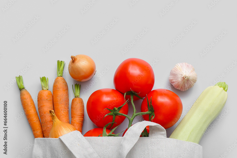 Eco bag with different fresh vegetables on light background