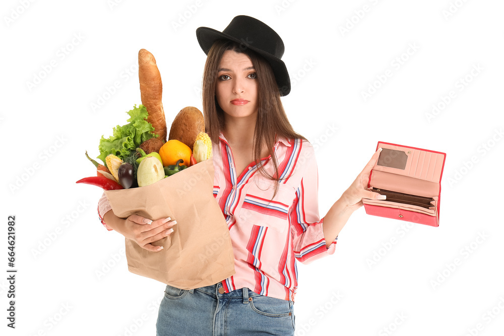 Young woman holding paper bag with fresh vegetables and empty wallet on white background