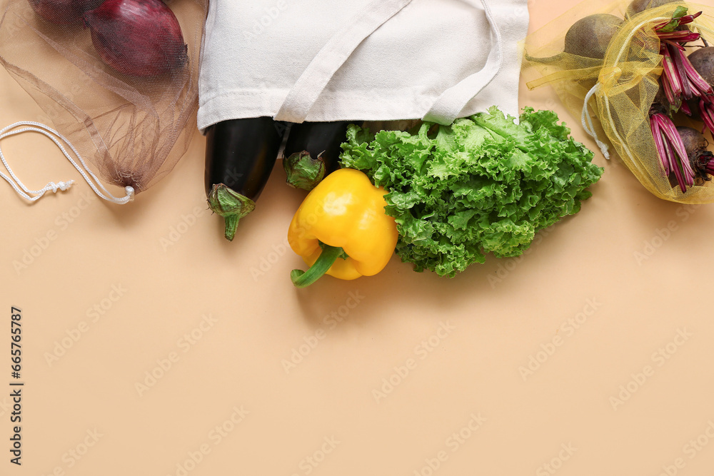 Eco bags with different fresh vegetables on beige background