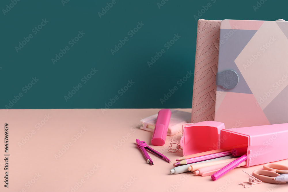 Pink pencil case with school stationery on school desk near blackboard