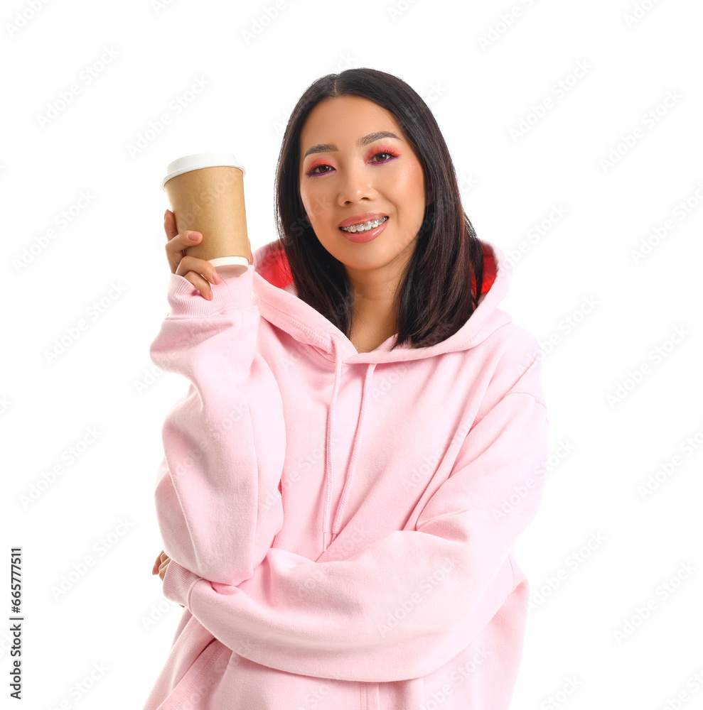 Young Asian woman in pink hoodie with coffee cup on white background