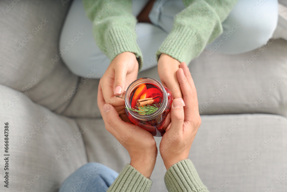 Couple with glass of warm mulled wine sitting on sofa in living room, top view