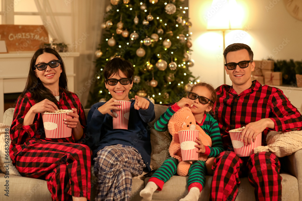 Happy family in 3D glasses with popcorn watching Christmas movie on TV at home