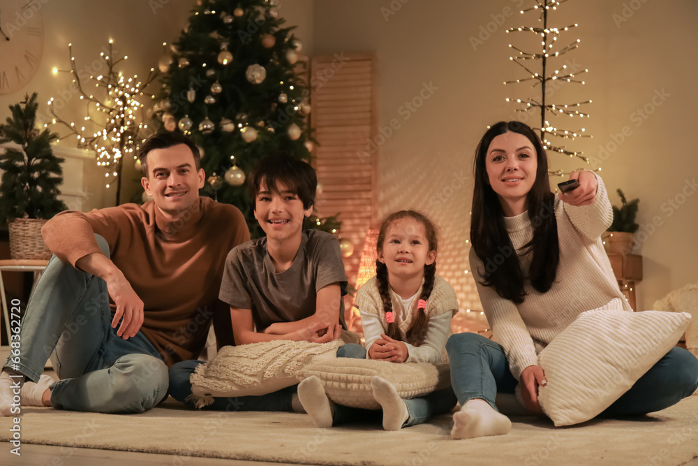 Happy family watching Christmas movie on TV at home