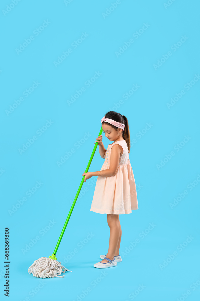 Cute little girl with mop on blue background