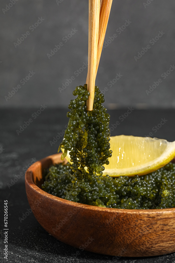 Bowl and chopsticks with healthy seaweed on dark background, closeup