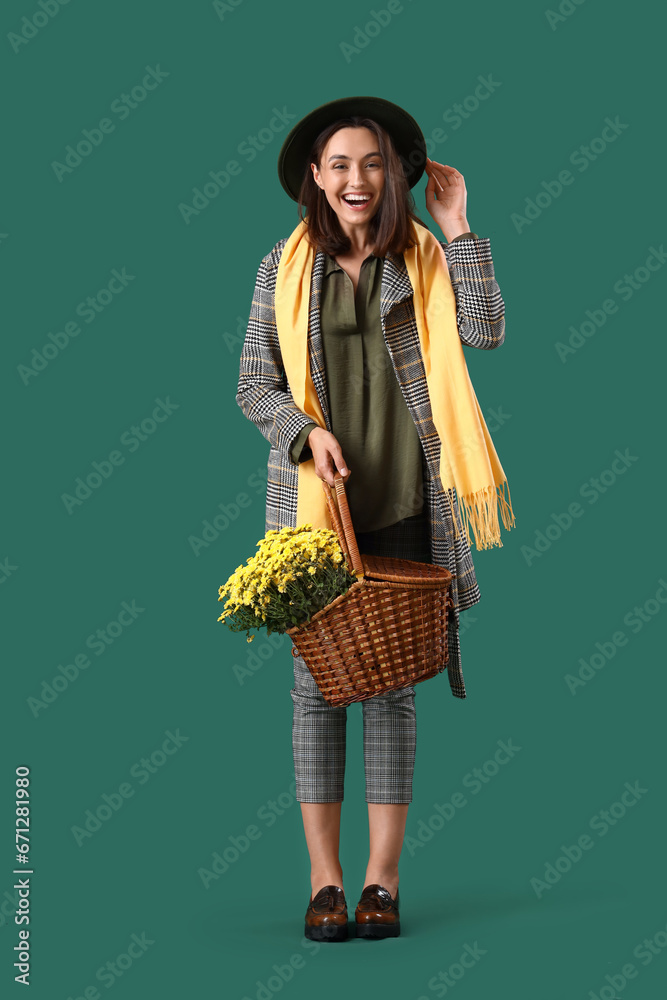 Young woman with chrysanthemum flowers on green background