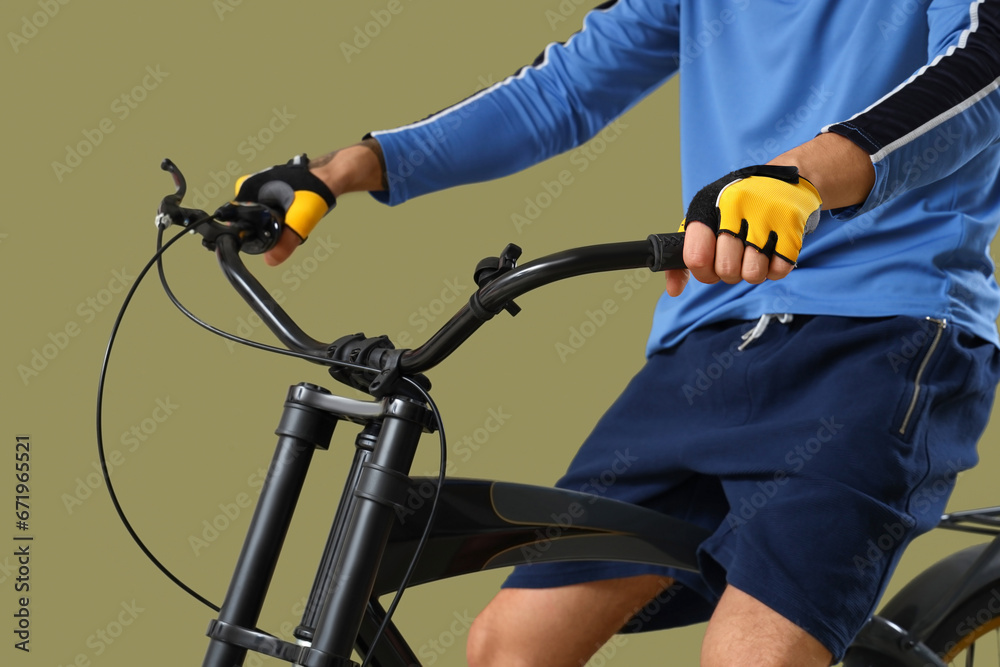 Young man riding bicycle on khaki background