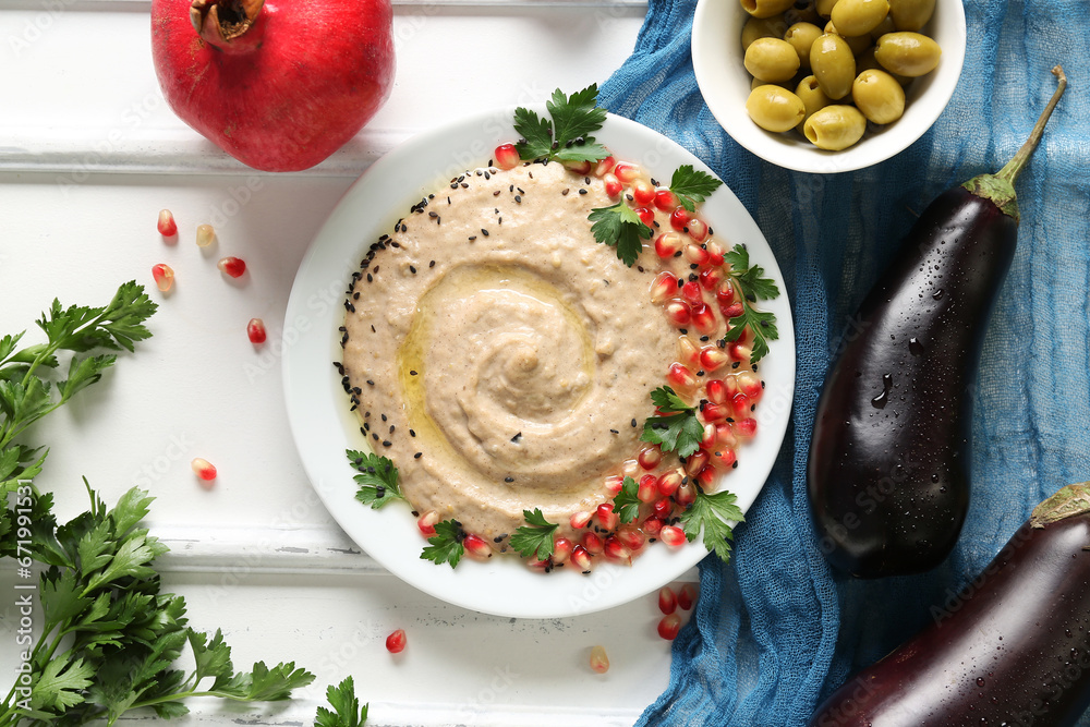 Plate of tasty baba ghanoush with ingredients on white wooden background