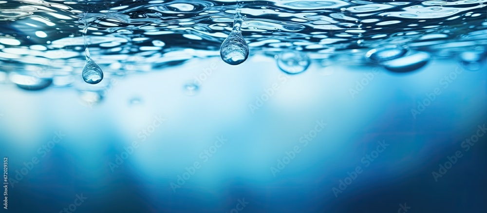 A tranquil and clear blue surface of water with gentle ripples The transparent and blurred texture of the water s surface appears calm with splashes and bubbles adding movement The backgrou