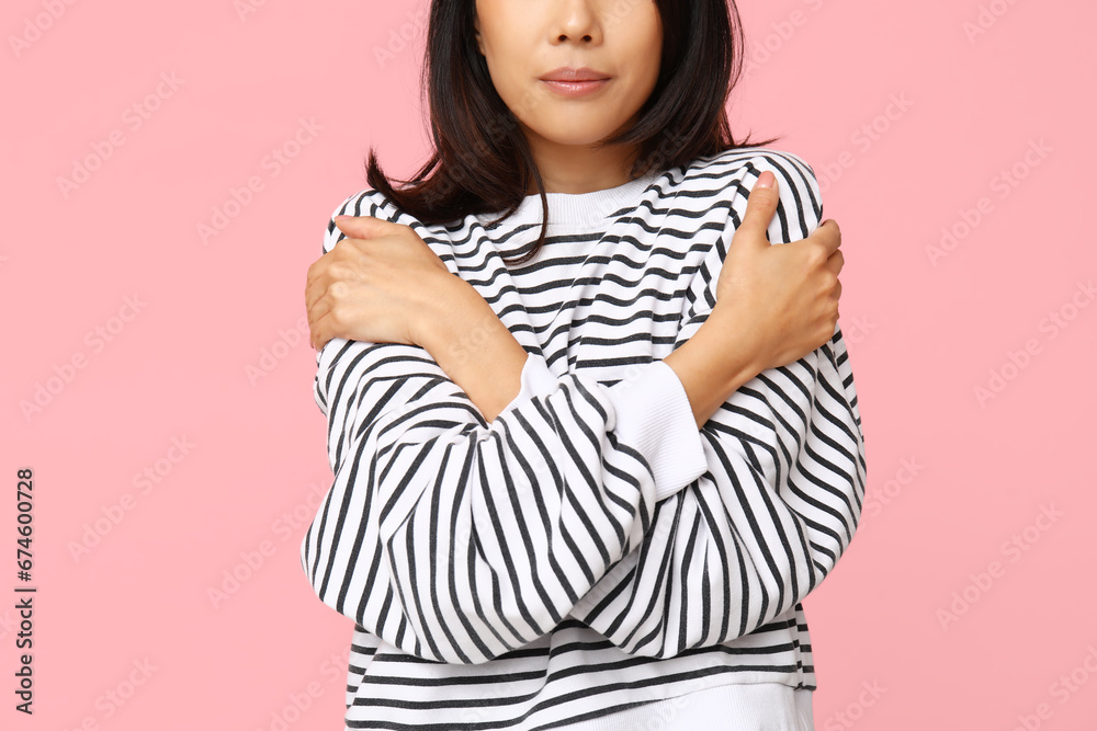 Young woman hugging herself on pink background, closeup