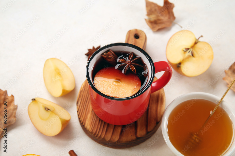 Cup of hot mulled wine with apple and bowl of honey on white background
