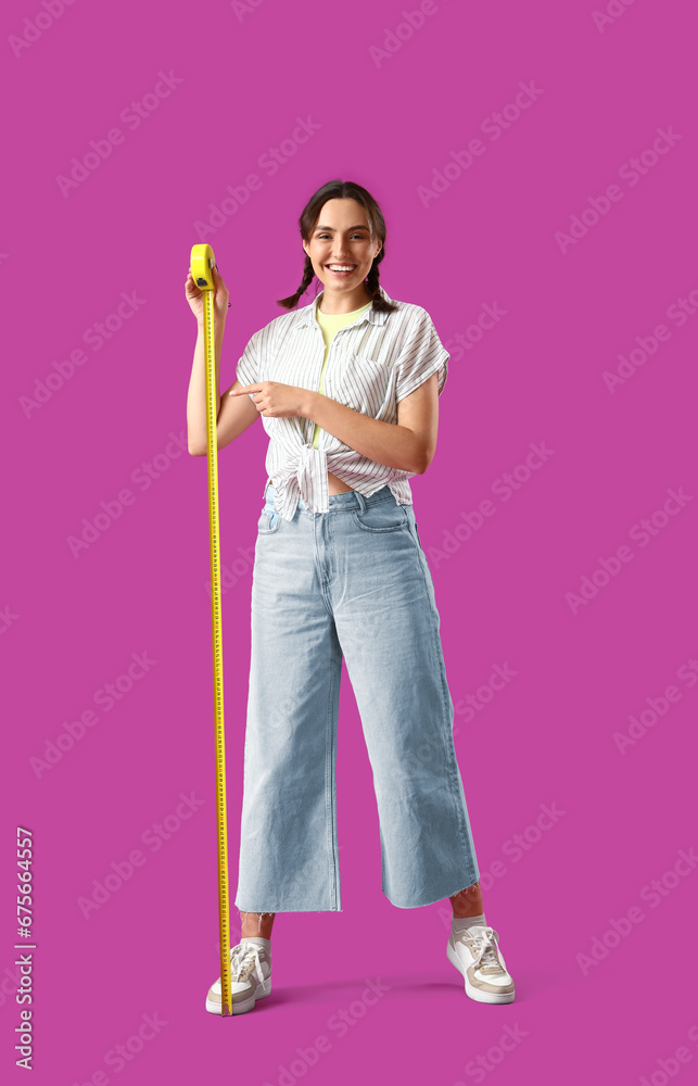 Young woman with tape measure on purple background