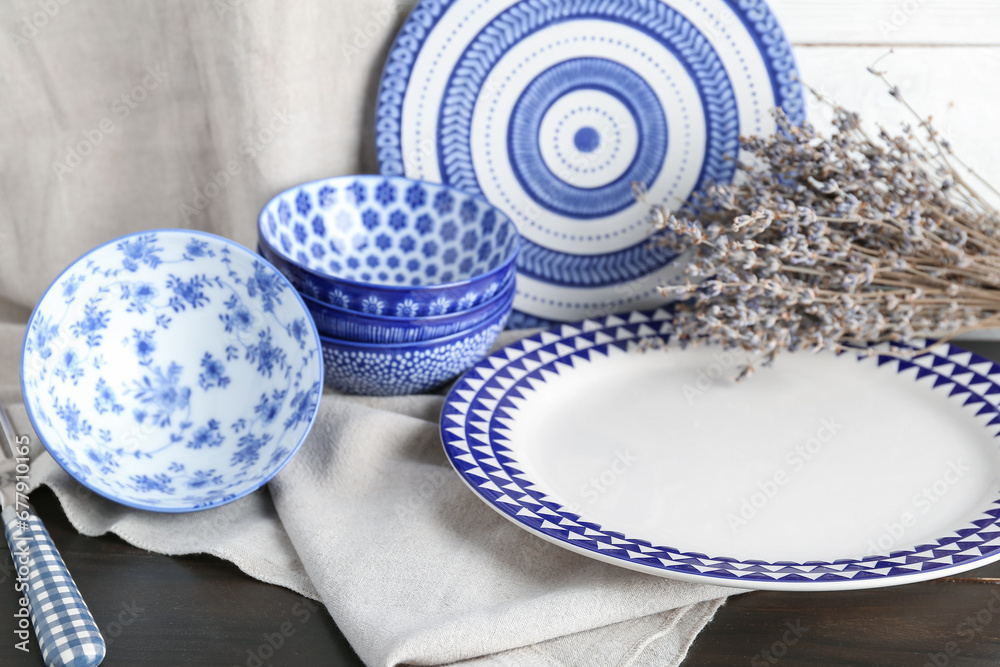 Set of clean blue dishes and dried lavender on black wooden table