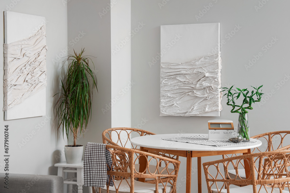 Interior of modern dining room with paintings, table and houseplant