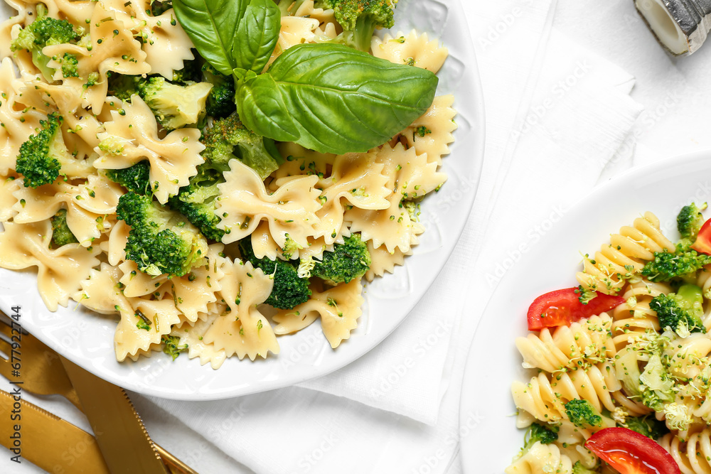 Plates of tasty pasta with broccoli on white background