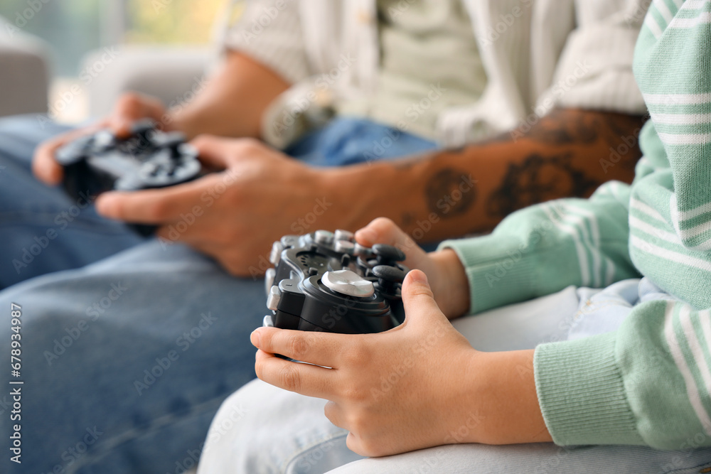 Young man with his little son playing video game at home, closeup
