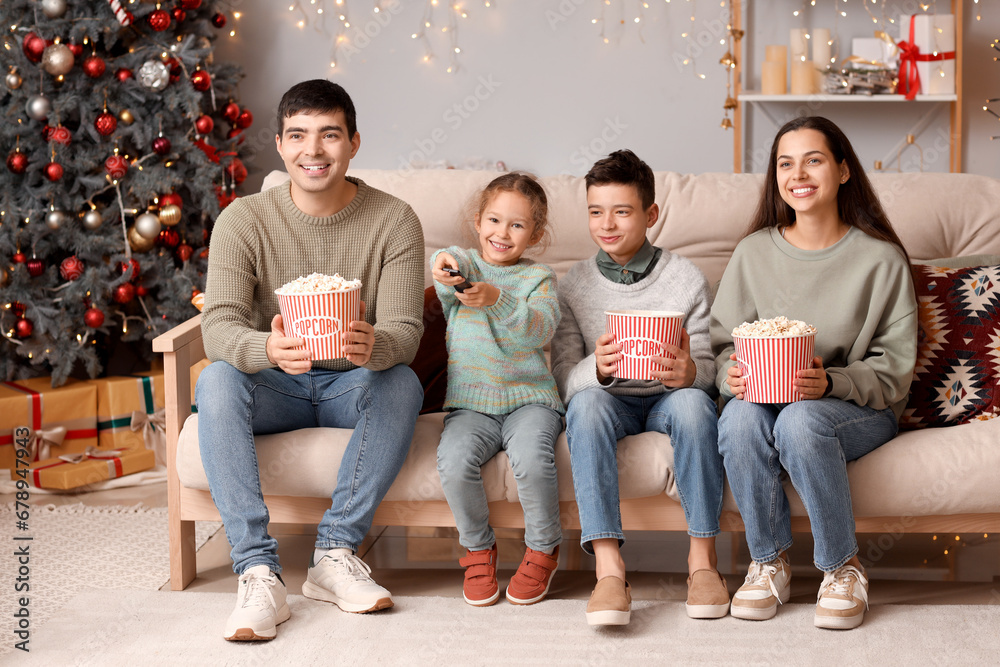 Happy family with popcorn watching Christmas movie on TV at home