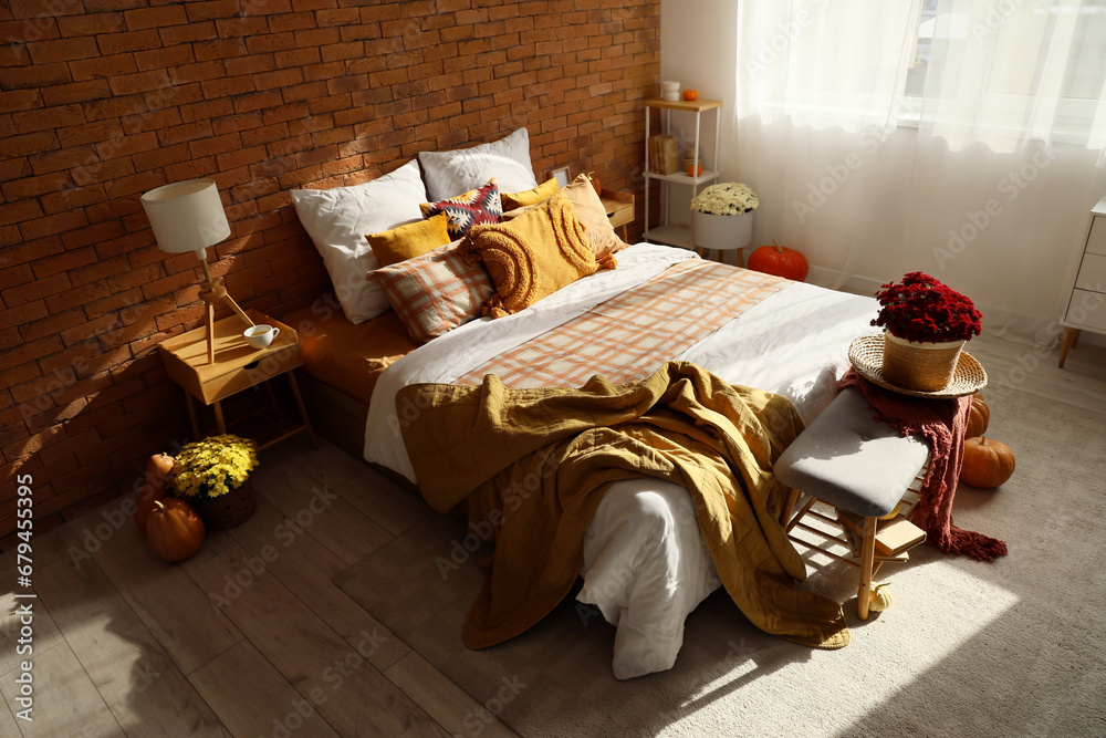 Interior of cozy bedroom with chrysanthemum flowers and pumpkins