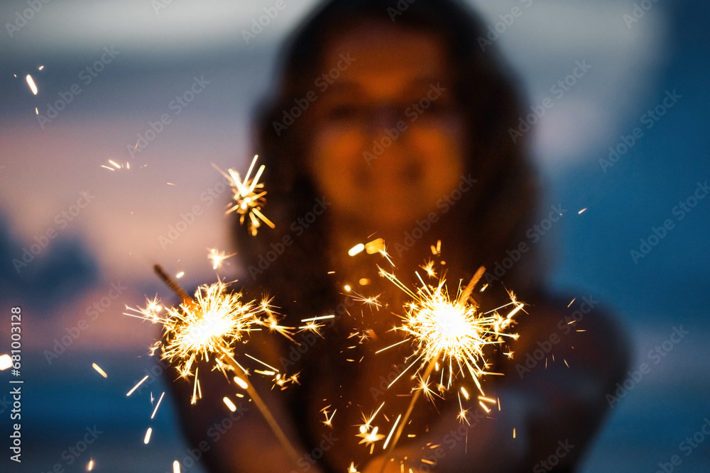 Young woman holding sparkler celebrating new years eve on the beach