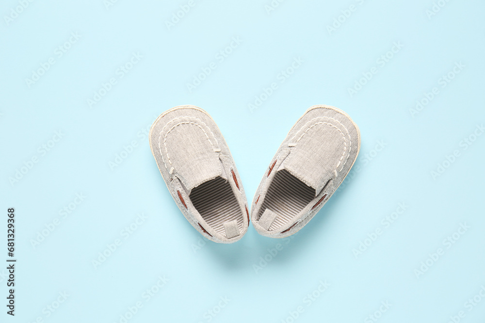 Stylish baby shoes on blue background