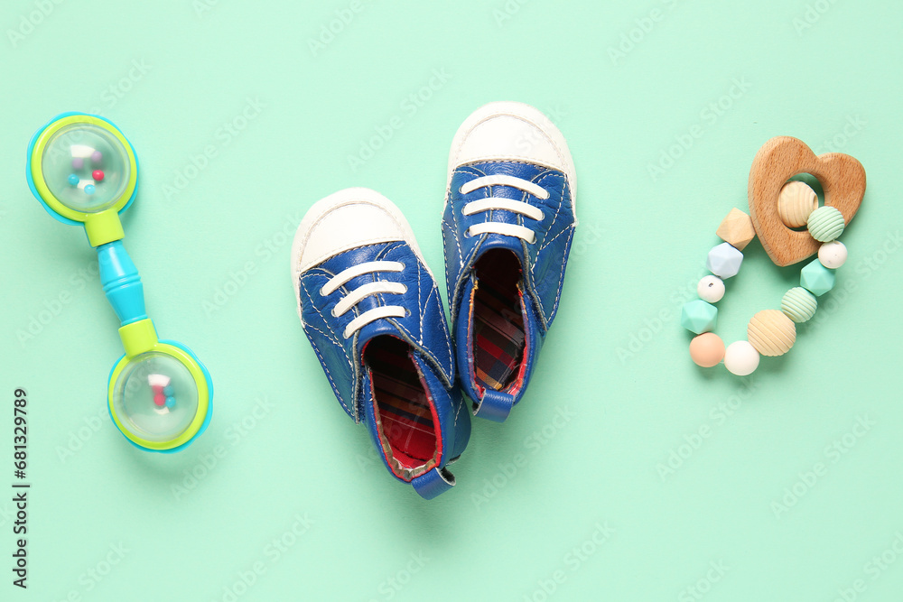 Stylish baby shoes with rattles on turquoise background